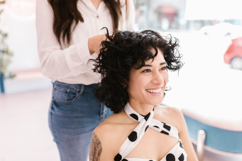 Uśmiechnięta kobieta w salonie beauty pokazuje zdjęcie z klientką, publikacja zdjęć klientek